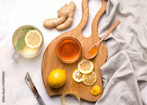 Drink with lemon, mint and ginger and honey next to the ingredients on a Wooden chopping board