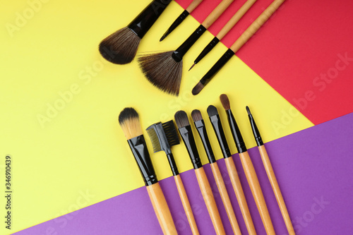 colorful flat lay with different makeup brushes and copy space