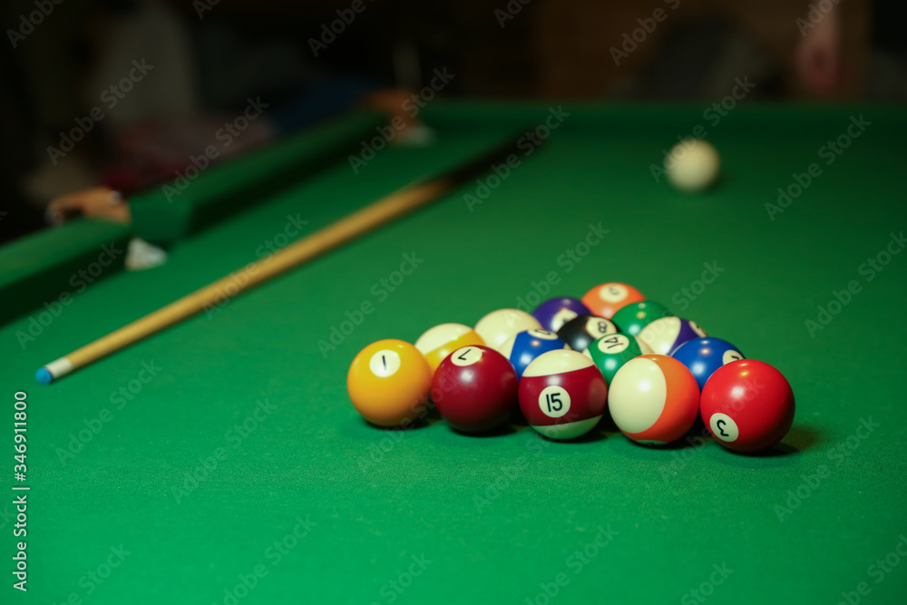 billiard cues and pyramid of multicolored pool balls on green billiard table billiard cues and pyramid of multicolored pool balls on green billiard table
