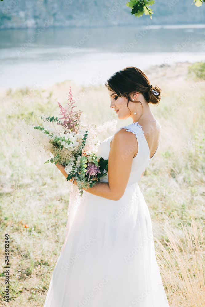 Bride in a luxurious white wedding dress in nature at sunset Bride in a luxurious white wedding dress in nature at sunset
