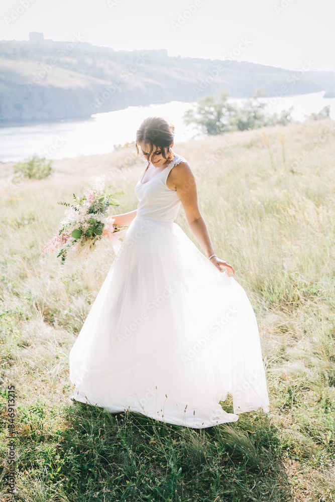 Bride in a luxurious white wedding dress in nature at sunset	
