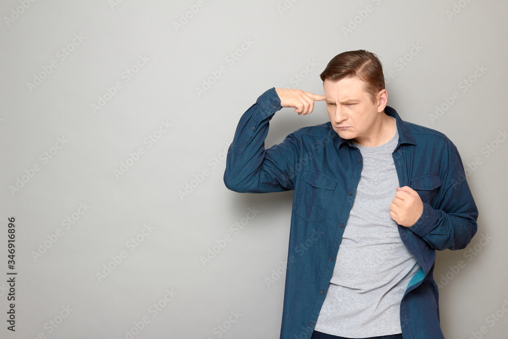 Portrait of funny thoughtful man touching head with finger and thinking hard Portrait of funny thoughtful man touching head with finger and thinking hard