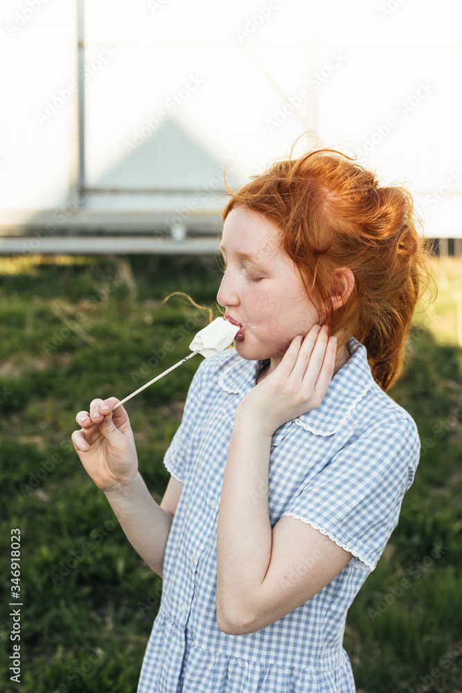 Red-haired girl eating hot marshmallow on a stick Red-haired girl eating hot marshmallow on a stick