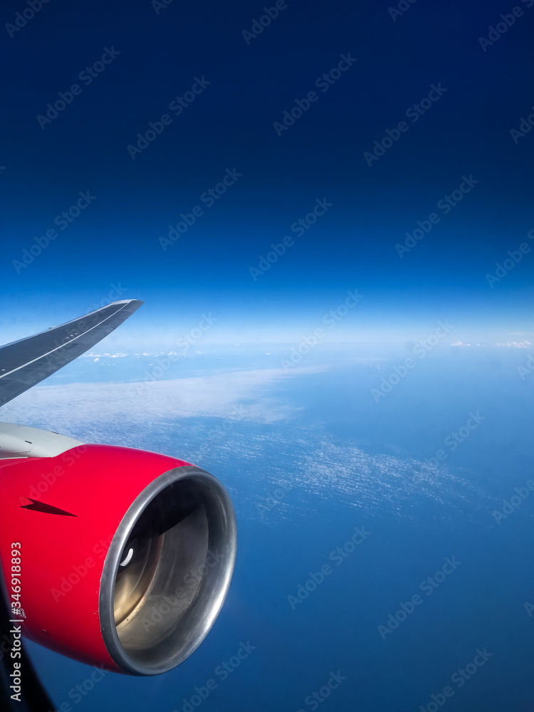 Fototapeta premium View from the airplane porthole of the turbine and the endless blue of the sky with rare clouds