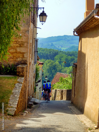 Fototapeta Naklejka Na Ścianę i Meble -  French cycling club descending the steep streets of Limeuil in Dordogne, France