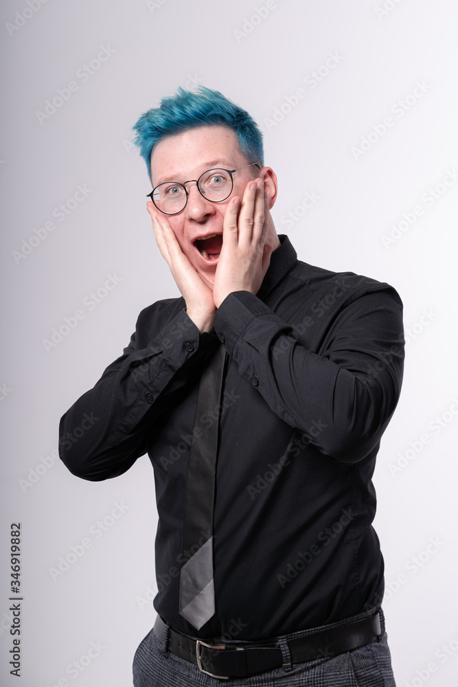Young stylish european man with blue hair expressing amazement, shock and excitement, opening his mouth widely and touching his face Young stylish european man with blue hair expressing amazement, shock and excitement, opening his mouth widely and touching his face