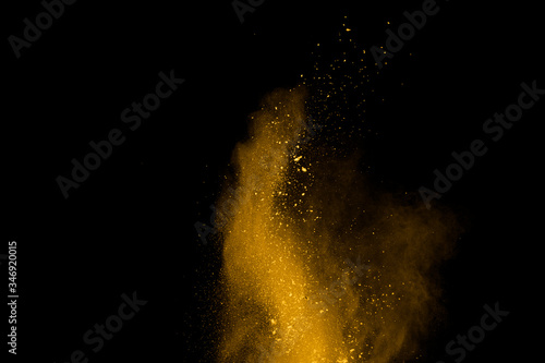 Yellow powder explosion on black background. Colored cloud. Colorful dust explode. Paint Holi.