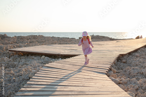 Happy pretty girl walks along the sea coast against the background of the sea, from behind a beautiful landscape