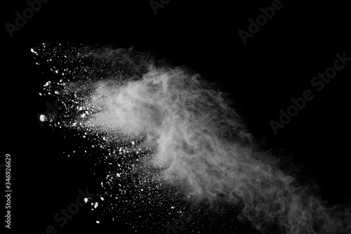 Freeze motion of white color powder exploding on black background.