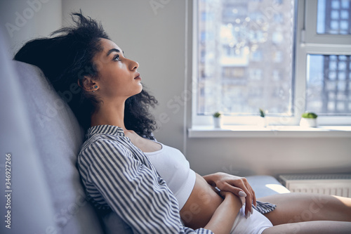Foto Despondent beautiful female sitting on the sofa