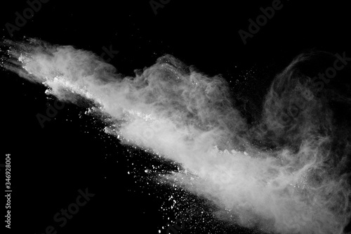 Freeze motion of white color powder exploding on black background.