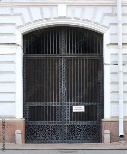 Large metal wrought-iron openwork gate with a sign in Russian, "Beware of the car"