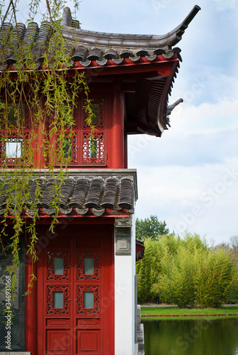 Chinese-style red-and-white house in a park on the river bank on a sunny day.