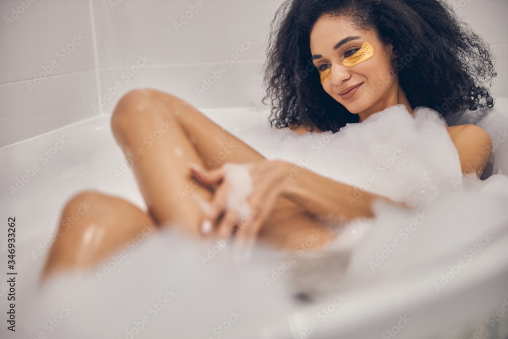 Obraz premium Smiling dark-haired girl enjoying her beauty procedure