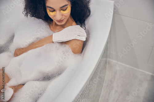 Calm young woman using an exfoliating glove