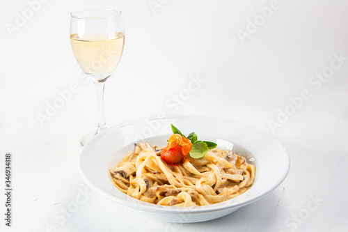Spaghetti dish served with sauce and accompanied by a glass of white wine