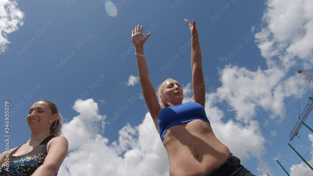 two young moms do outdoor exercises. flexibility training - pretty blonde girl performs exercise& aerobics and outdoor fitness. a pilates workshop. gymnastics at a summer mountain resort two young moms do outdoor exercises. flexibility training - pretty blonde girl performs exercise& aerobics and outdoor fitness. a pilates workshop. gymnastics at a summer mountain resort