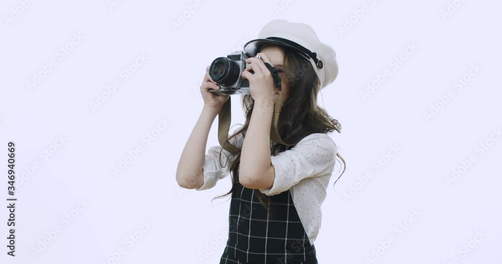 Pretty and cute small stylish Caucasian girl in a hat taking photos with a photocamera and smiling joyfully on the white wall background. Pretty and cute small stylish Caucasian girl in a hat taking photos with a photocamera and smiling joyfully on the white wall background.