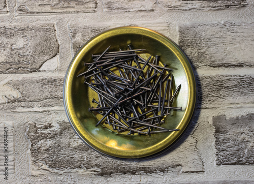 Black Nails on a metal stand against a brick wall.