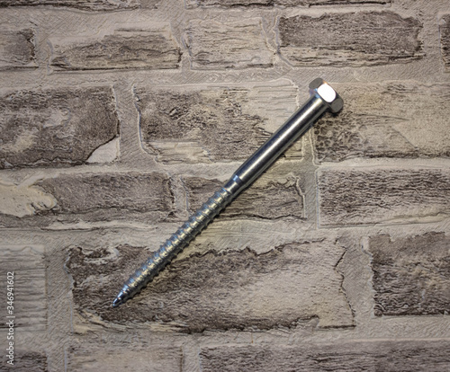 Anchor plug with universal wrench screw against a brick wall.