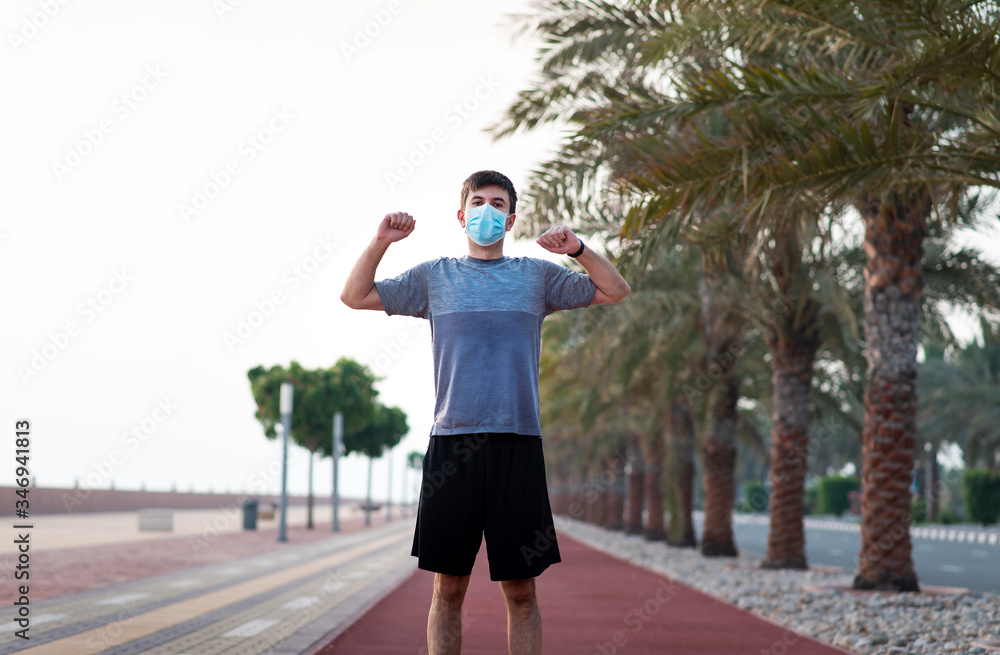 Man exercising outdoors and wearing protective surgical mask