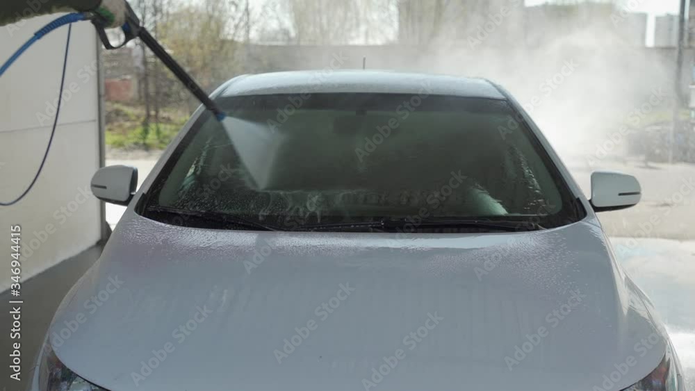A man is washing a car at self service car wash. High pressure vehicle washer machine clean with water. Car wash equipment A man is washing a car at self service car wash. High pressure vehicle washer machine clean with water. Car wash equipment