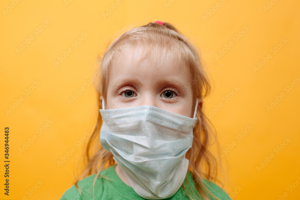 A Small Child In a White Medical Mask on a Yellow Background. Coronavirus. Protecting Children From The Epidemic. Space For Text A Small Child In a White Medical Mask on a Yellow Background. Coronavirus. Protecting Children From The Epidemic. Space For Text