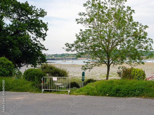 Closed beach entrance during the COVID-19 epidemic. In the background the ocean at low tide. Sailboats and yachts visible.