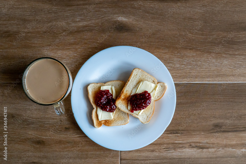 Cup of coffe with milk and two slices of toasted sandwich with Butter and Raspberry Jam. Breakfast with coffee. Top view. Free space for text.
