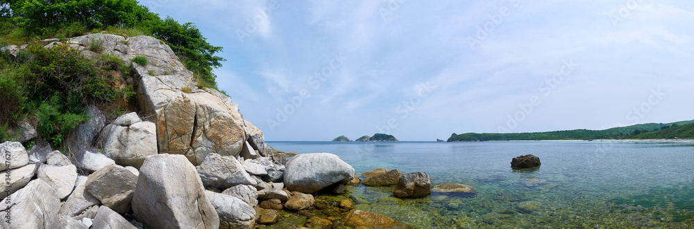 Sea coast with clear water. Stones and sea urchins at the bottom. Panorama with the sea coast.