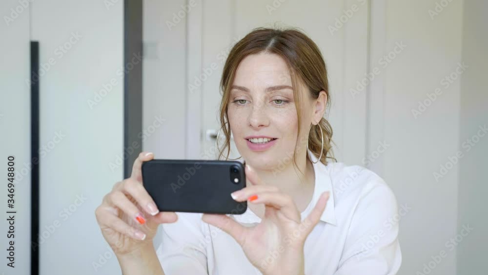 Happy relaxed young woman holding smartphone looking at cellphone screen laughing enjoying using mobile apps for shopping having fun playing games chatting in social media sit on room at home 4k Happy relaxed young woman holding smartphone looking at cellphone screen laughing enjoying using mobile apps for shopping having fun playing games chatting in social media sit on room at home 4k