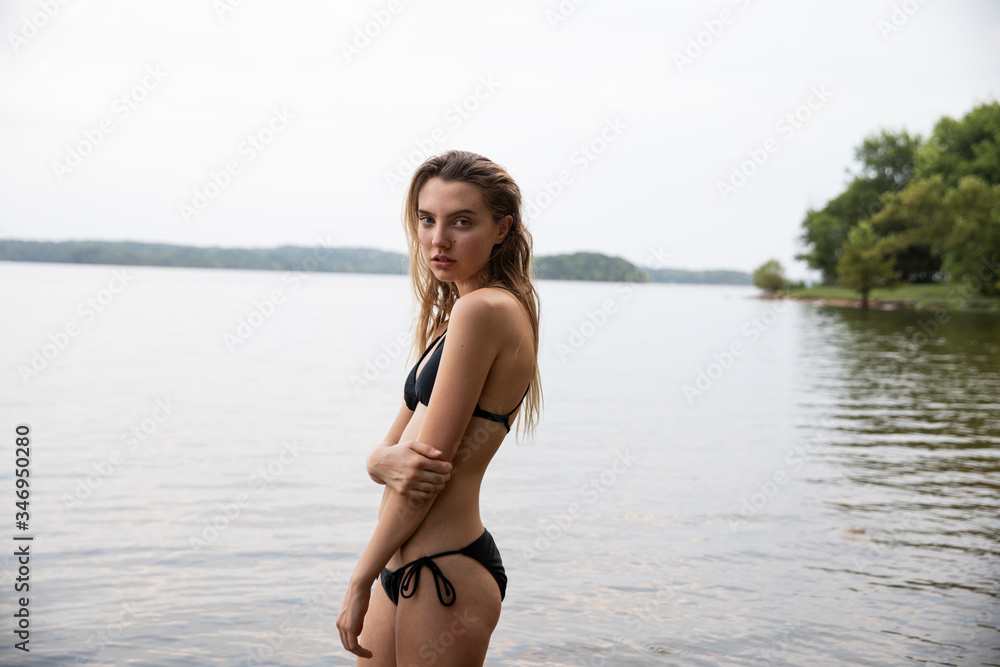 Young female wearing a bikini, lake in the background, looking at camera. Young female wearing a bikini, lake in the background, looking at camera.