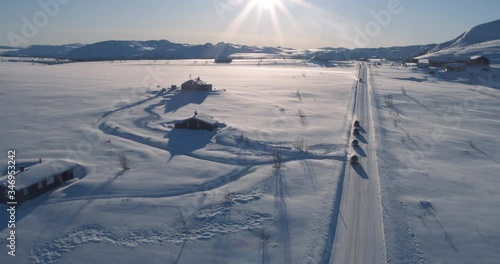 Aerial of four cars driving on the snowy mountain in Norway. 