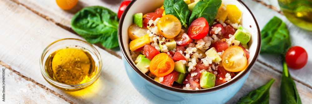 Concept of healthy food, clean eating, low calories delicious meal. Salad with quinoa and fresh vegetables with olive oil in blue bowl. Tomato, avocado, spinach. Close up wooden background, banner Concept of healthy food, clean eating, low calories delicious meal. Salad with quinoa and fresh vegetables with olive oil in blue bowl. Tomato, avocado, spinach. Close up wooden background, banner