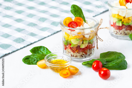 Concept of healthy food, clean eating, low calories delicious meal. Salad with quinoa and fresh vegetables with olive oil in glass jar. Zero waste no plastic. Close up white background copy space