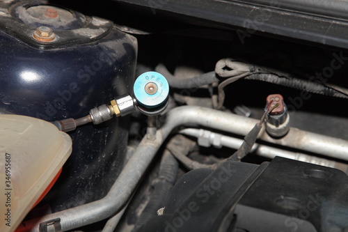 Car A/C blue low pressure valve on sensor in big pipe engine compartment of the car, vehicle air conditioner vacuuming, repair service and refilling