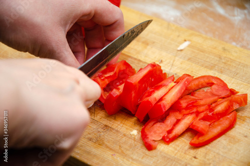 Hands cut tomatoes on the board. Tomatoes on a chopped pizza board. Sliced tomatoes