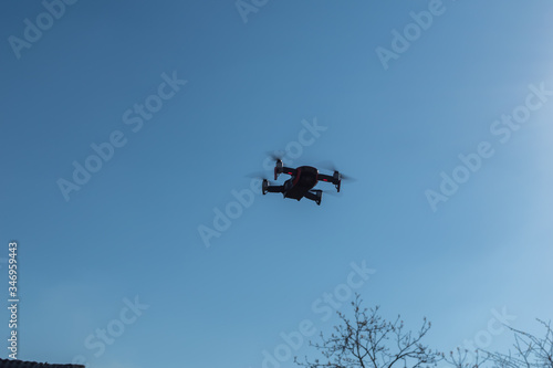 Fototapeta Naklejka Na Ścianę i Meble -  Small sized red drone with high resolution camera hovering in air for aerial photography.