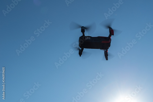 Small sized red drone with high resolution camera hovering in air for aerial photography.