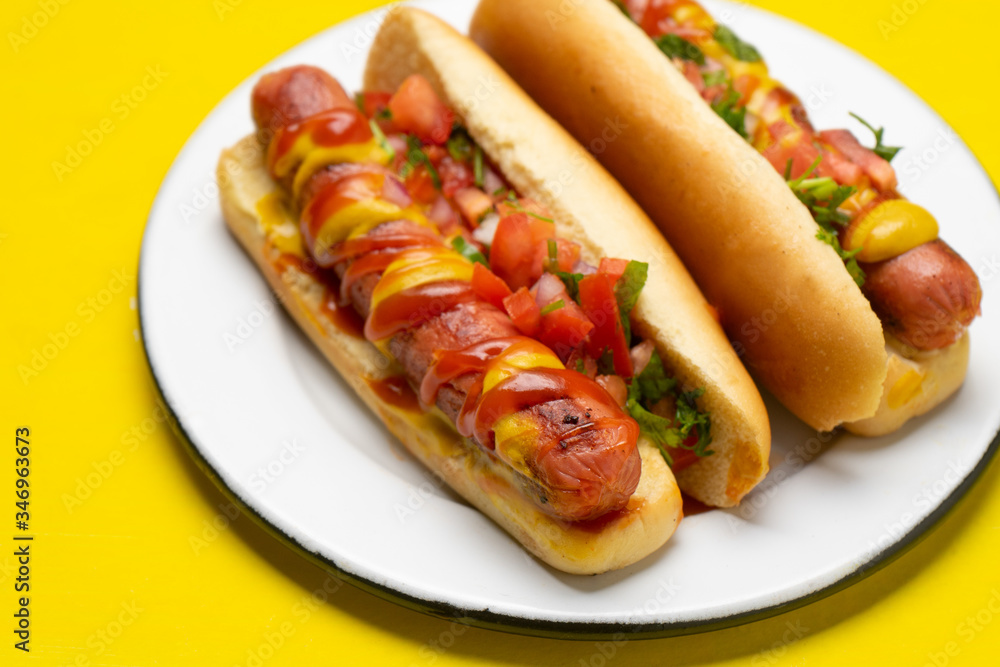 Hot dog with pico de gallo salad on yellow background Hot dog with pico de gallo salad on yellow background