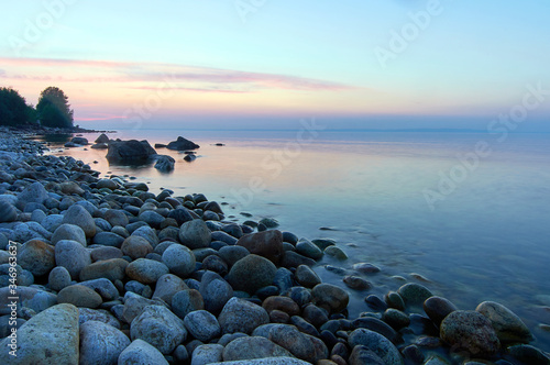 Lake Baikal in the summer at dawn. In the foreground is clear water and stones under water.