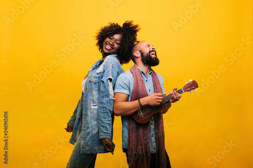 Happy young man with woman in studio playing ukulele