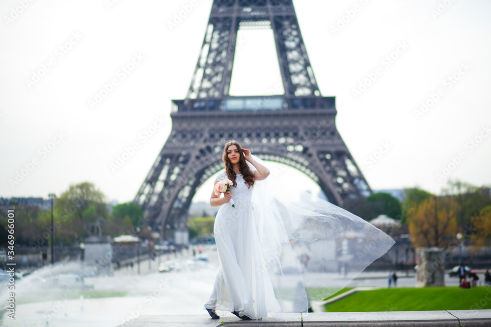 Obraz premium Beautiful bride in rich wedding dress whirls on the square before the Eiffel Tower