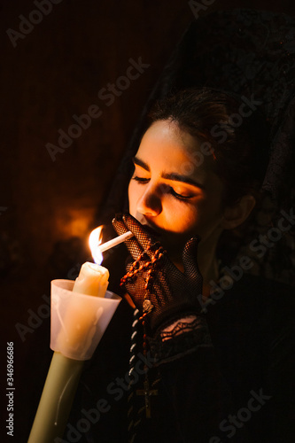 Beautiful woman made up in traditional costume for la semana santa, lighting cigarette on burning candle