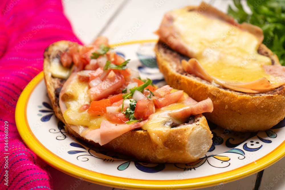 Mexican molletes with ham and cheese on white background