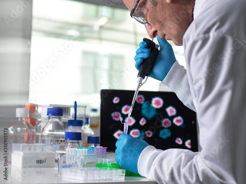 Pharmaceutical research into infectious disease and pandemics, scientist pipetting a sample of a new drug formula into a vial during a clinical trial with the infectious disease on the computer screen photo