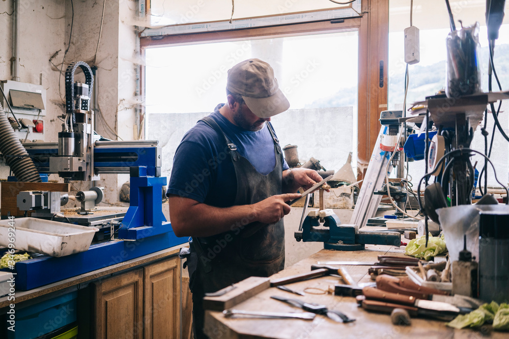 Craftsman making knives in his workshop examining the blade Craftsman making knives in his workshop examining the blade