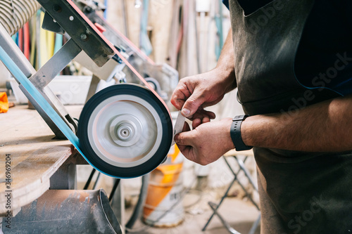 Craftsman making knives in his workshop sharpening the blade