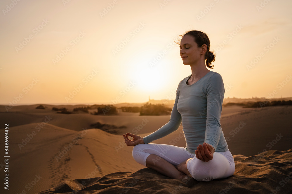 Woman practicing yoga in sand dunes at sunset, Gran Canaria, Spain Woman practicing yoga in sand dunes at sunset, Gran Canaria, Spain