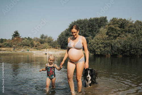 Netherlands, Schiermonnikoog, pregnant mother with daughter and Border Collie in a lake photo